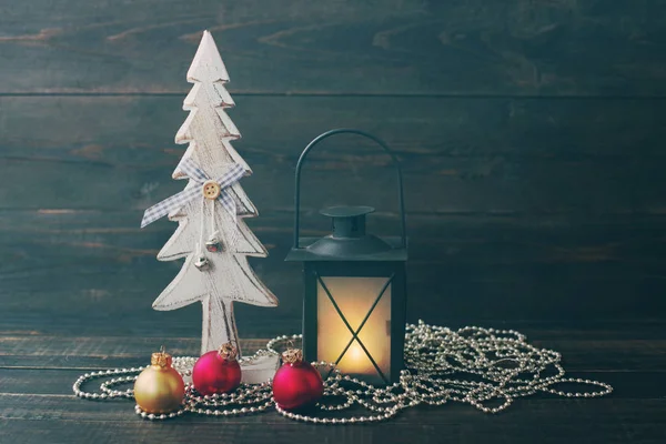 Abeto decorativo de año nuevo de madera, lámpara de Navidad y esferas de vidrio sobre un fondo de madera . —  Fotos de Stock