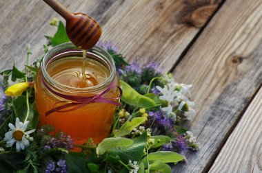 Çiçekler bir cam kavanoza bir ahşap yüzeyde melliferous otlar tatlım. 