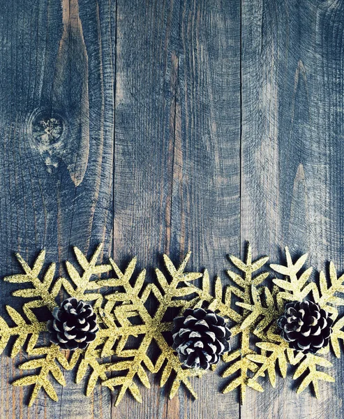 Weihnachten Holzhintergrund mit dekorativen Schneeflocken und Tannenzapfen. Schneeflocken auf einem Holzbrett. — Stockfoto