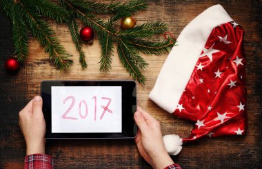 Tablet Pc elinde tutan çocuk. Noel Baba'nın kap, Noel süsleri ve 2017 bir yastık üzerinde bir metin ile köknar ağacı dalları.