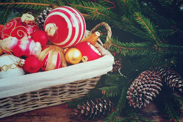 Cesta con juguetes y bolas de vidrio de colores, conos, decoración y regalos sobre fondo de madera. Fondo de Navidad o Año Nuevo . — Foto de Stock