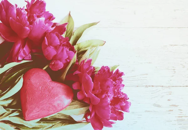 Bouquet di peonie rosa e cuore di legno rosso sul vecchio sfondo in legno dipinto — Foto Stock