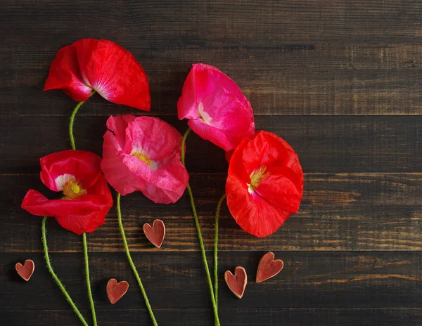 Flores de amapola silvestre rosa y corazones de madera roja. Imagen romántica festiva del Día de San Valentín —  Fotos de Stock