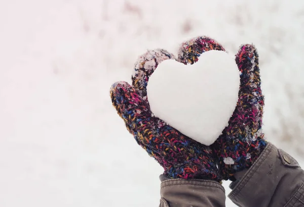 Meisje met hart van sneeuw in gebreide wanten in de winter. Valentine achtergrond. — Stockfoto