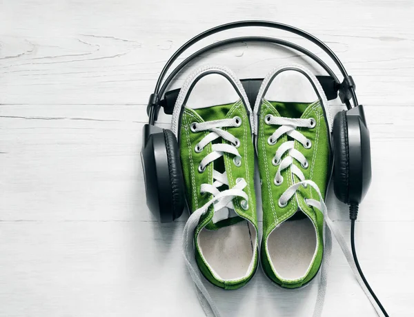 Konzept mit grünen Turnschuhen und schwarzen Kopfhörern — Stockfoto