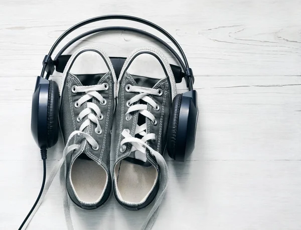 Έννοια με γκρι πάνινα παπούτσια και μαύρα ακουστικά — Φωτογραφία Αρχείου