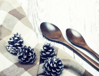 Tahta kaşık ve bir beyaz eski ahşap yüzeye çam kozalakları.