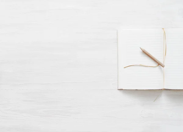Notitieboekje met lege pagina's en een potlood op een witte houten ondergrond — Stockfoto