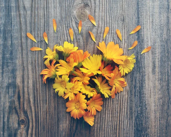 Yellow summer flowers in the form of heart on a wooden board in vintage tones. — Stock Photo, Image