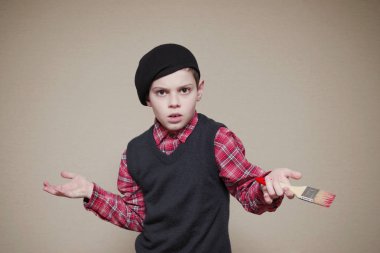 Çocuk hafif bir arka plan üzerinde bir boya fırçası ile bir bere içinde. 