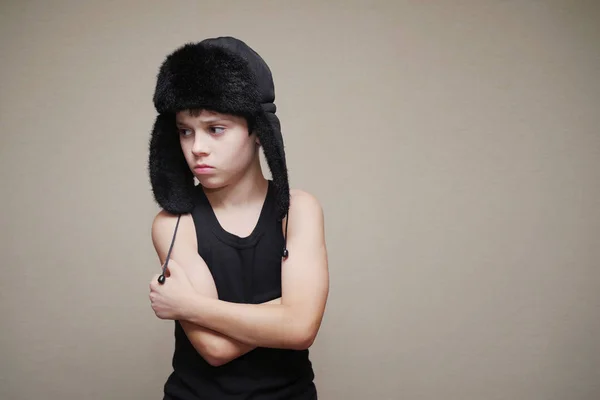 Garçon dans une casquette avec des oreillettes et un maillot de bain gymnastique sur un fond clair . — Photo