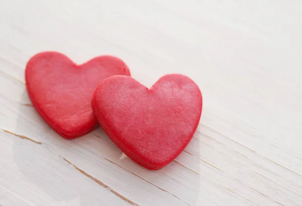 Two red hearts on a wooden white background, soft focus. Romantic card. — Stock Photo, Image