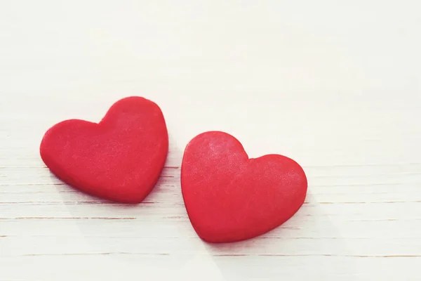 Dois corações vermelhos em um fundo branco de madeira, foco suave. Cartão romântico . — Fotografia de Stock