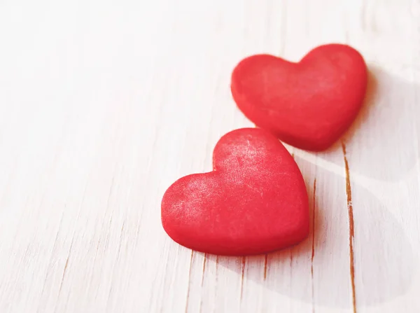 Two red hearts on a wooden white background, soft focus. Romantic card. — Stock Photo, Image