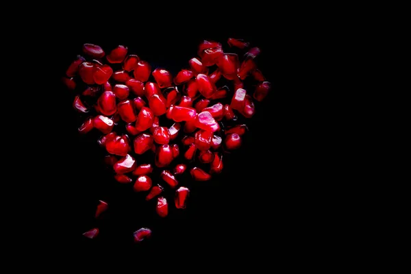 Siyah bir yüzey üzerinde nar kırmızı sulu taneleri yürekten. — Stok fotoğraf