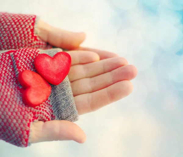 Two red decorative hearts in female hands on a light background. Romantic card — Stock Photo, Image