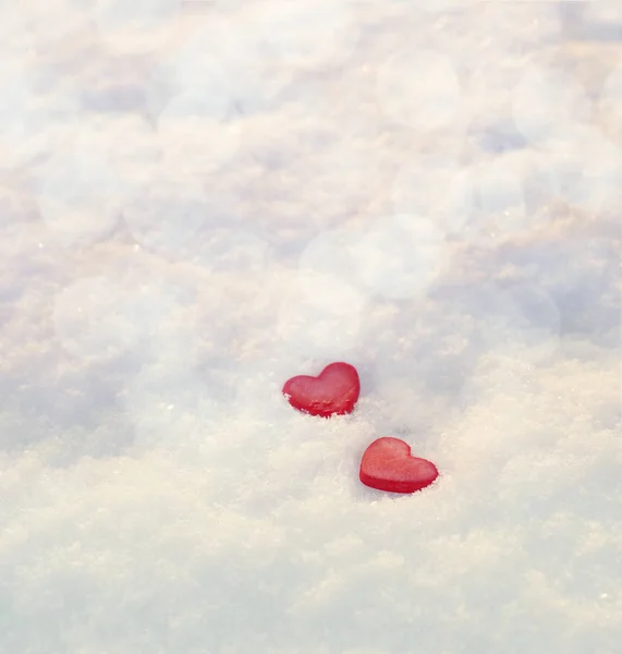 雪の上の 2 つの赤いハート。ロマンチックな背景 — ストック写真