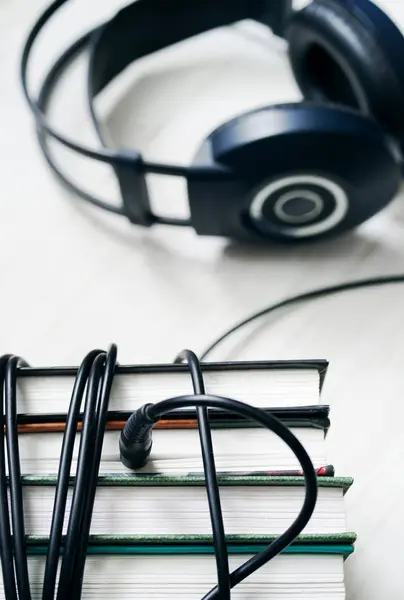 Boeken en koptelefoon op houten witte oppervlak. — Stockfoto