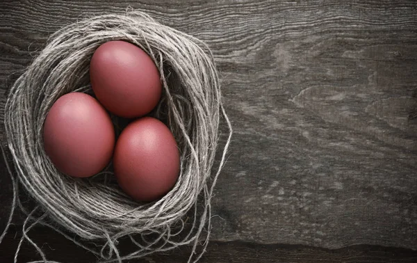 Easter eggs in a nest on a wooden background — Stock Photo, Image