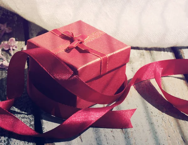 Gift red box with a bow on a wooden background. — Stock Photo, Image