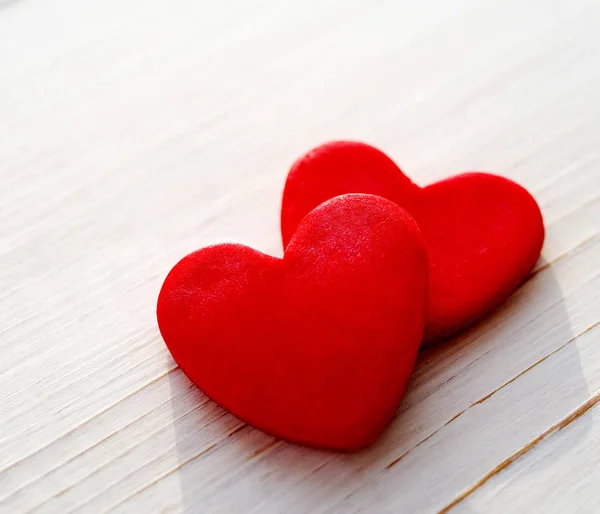 Twee rode harten op een houten witte achtergrond, zachte focus. Romantische kaart. — Stockfoto