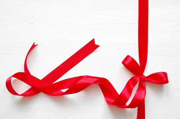 Red ribbon bow on a white wooden background. — Stock Photo, Image