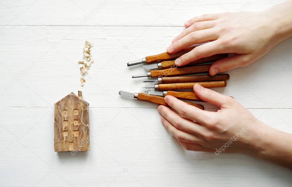 Wooden house and graver chisels with the master's hands 