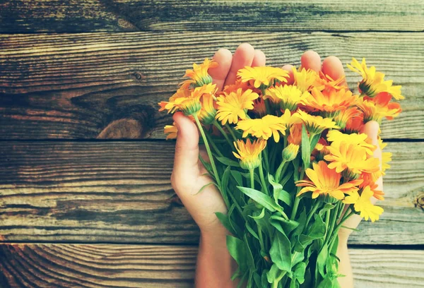 Fiori di estate in mani femminili contro una superficie di legno gialli. Mazzo festivo — Foto Stock