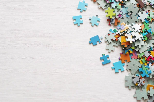 Pedaços de puzzle em uma superfície de madeira branca — Fotografia de Stock