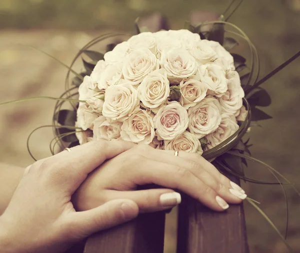 Hands of newlyweds and a wedding bouquet from roses — Stock Photo, Image
