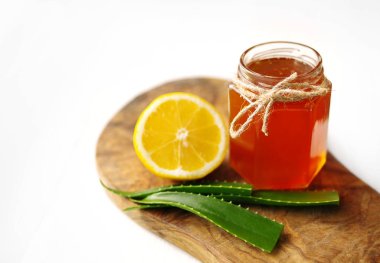 Bir cam kavanoz, limon ve beyaz zemin üzerine ahşap bir gemide aloe vera tatlım. 