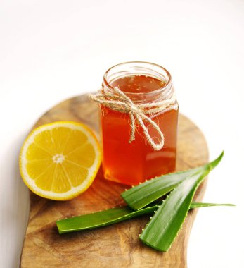 Bir cam kavanoz, limon ve beyaz zemin üzerine ahşap bir gemide aloe vera tatlım. 