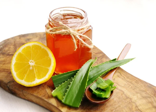 Bir cam kavanoz, limon ve beyaz zemin üzerine ahşap bir gemide aloe vera tatlım. 