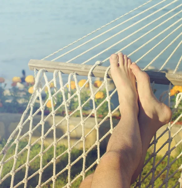 Mężczyzna nogi w hamaku na plaży przed morza w słoneczny letni dzień. — Zdjęcie stockowe