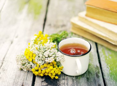 Bir demir beyaz kupa ve sarı çiçekler bir solucan otu ve civanperçemi bitkisel çay 