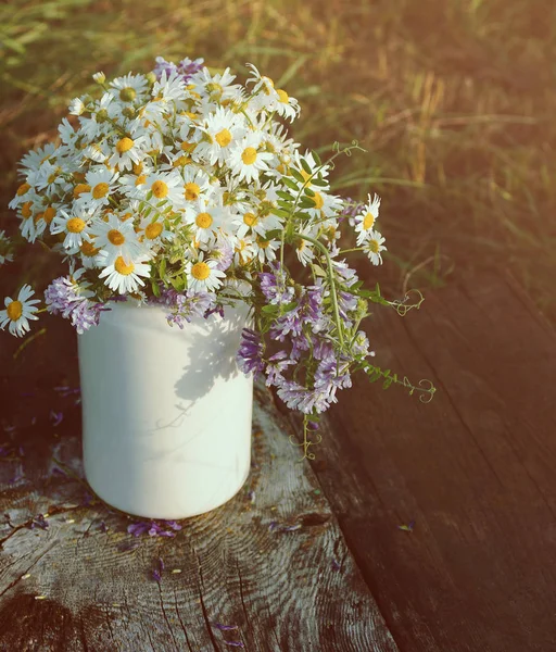 Bouquet of field camomiles in a white jug on an old wooden surface. — Stock Photo, Image