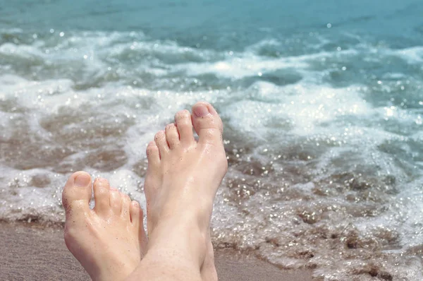 Kvinnliga fötter på en strand mot havet i en solig sommardag. — Stockfoto