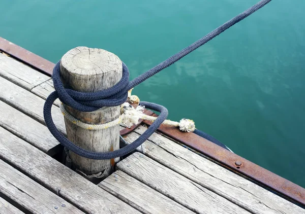 Деревянная куча со скрученной веревкой на причале — стоковое фото