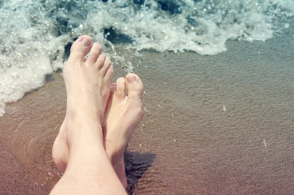 Pies femeninos en una playa contra el mar en un día soleado de verano . — Foto de Stock