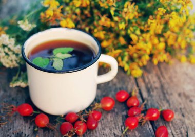 Bir demir kupa, kırmızı kuşburnu ve St John's Wort çiçek bitki çayı