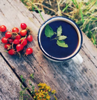 Bir demir kupa, kırmızı kuşburnu ve St John's Wort çiçek bitki çayı