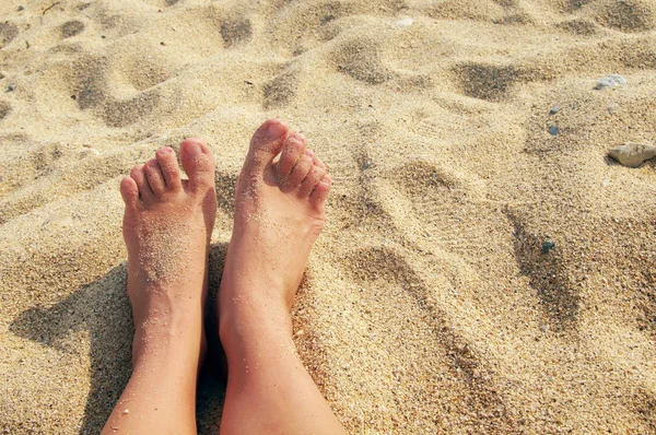 Kvinnliga ben på sea sand på stranden i soliga sommardag. — Stockfoto