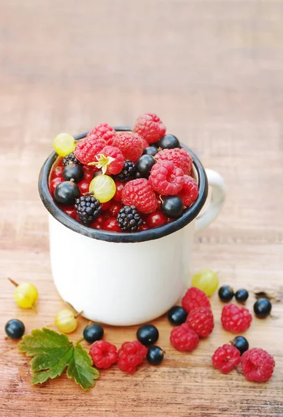Fresas bayas jugosas, frambuesas, grosellas, moras, grosellas en una taza de hierro blanco —  Fotos de Stock