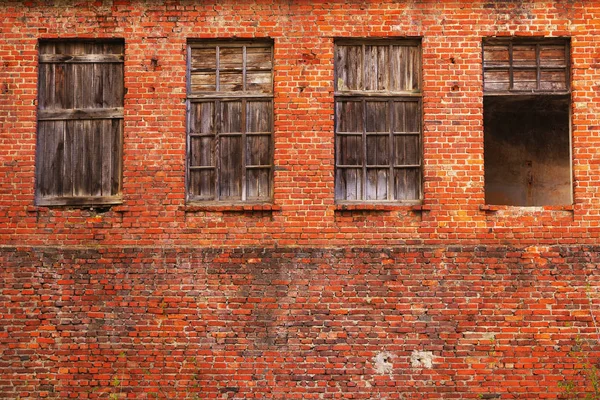 Стіна з червоної цегли з дерев'яними забитими вікнами. Стіна старої покинутої будівлі . — стокове фото