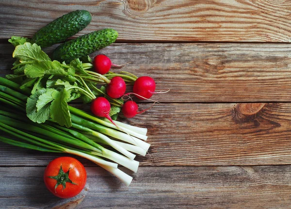 Cipolle verdi fresche, ravanello da giardino, cetrioli e pomodoro su una tavola di legno — Foto Stock