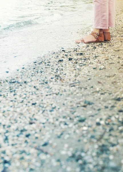 Vrouwelijke voeten in lederen sandalen op een zee-strand in een zomerdag — Stockfoto