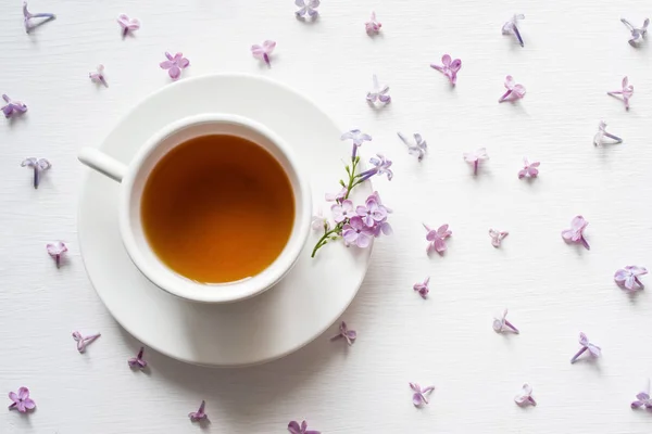 ライラックの花の環境の受け皿にお茶のカップ — ストック写真