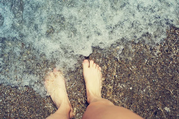 Pies femeninos en una playa contra el mar, vista superior. Vacaciones en el mar . —  Fotos de Stock