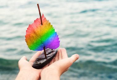 Bir gökkuşağı Lgbt içinde bir yelken ile küçük dekoratif yelkenli deniz arka planı elinde renkler. 