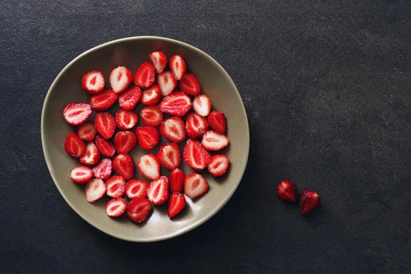 Сочные ягоды клубники в тарелке на темной поверхности — стоковое фото